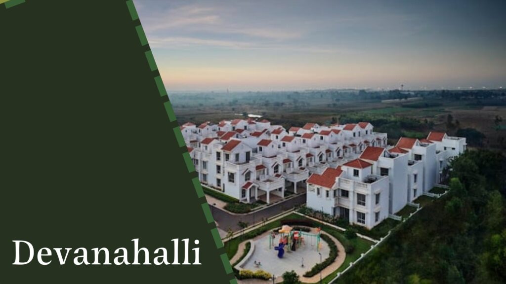 Aerial view of a residential complex with white houses and red roofs in Devanahalli, surrounded by greenery, with a playground in the foreground, showcasing the expertise of house construction companies in Bangalore.