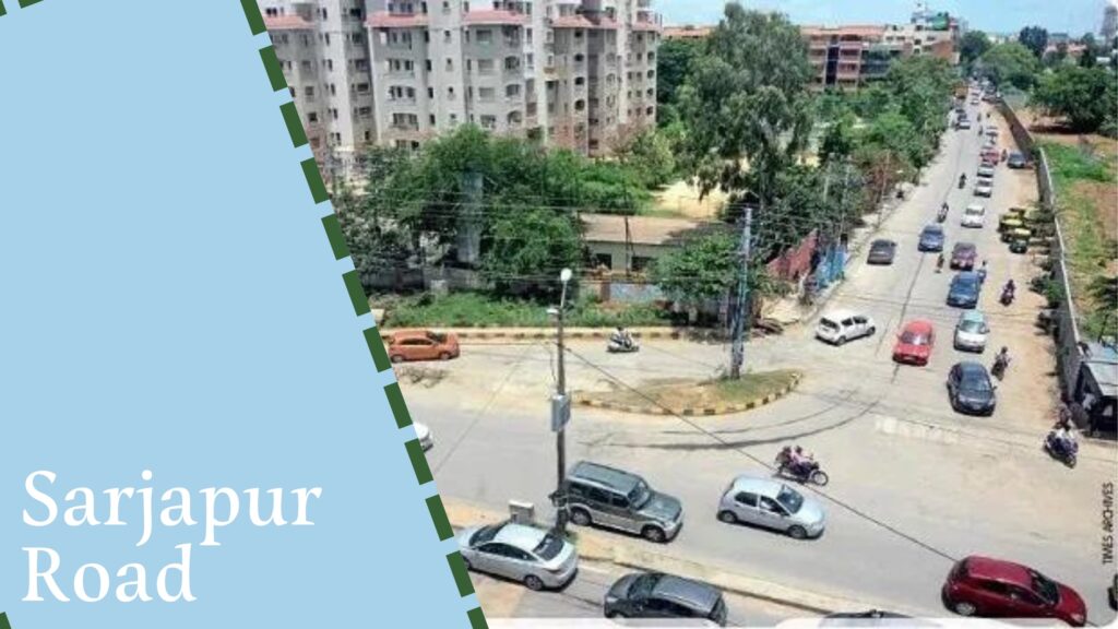 A street view of Sarjapur Road in Bangalore, showing traffic, multiple residential buildings, and greenery, taken from a higher vantage point. The bustling area is dotted with ongoing projects by house construction companies in Bangalore.